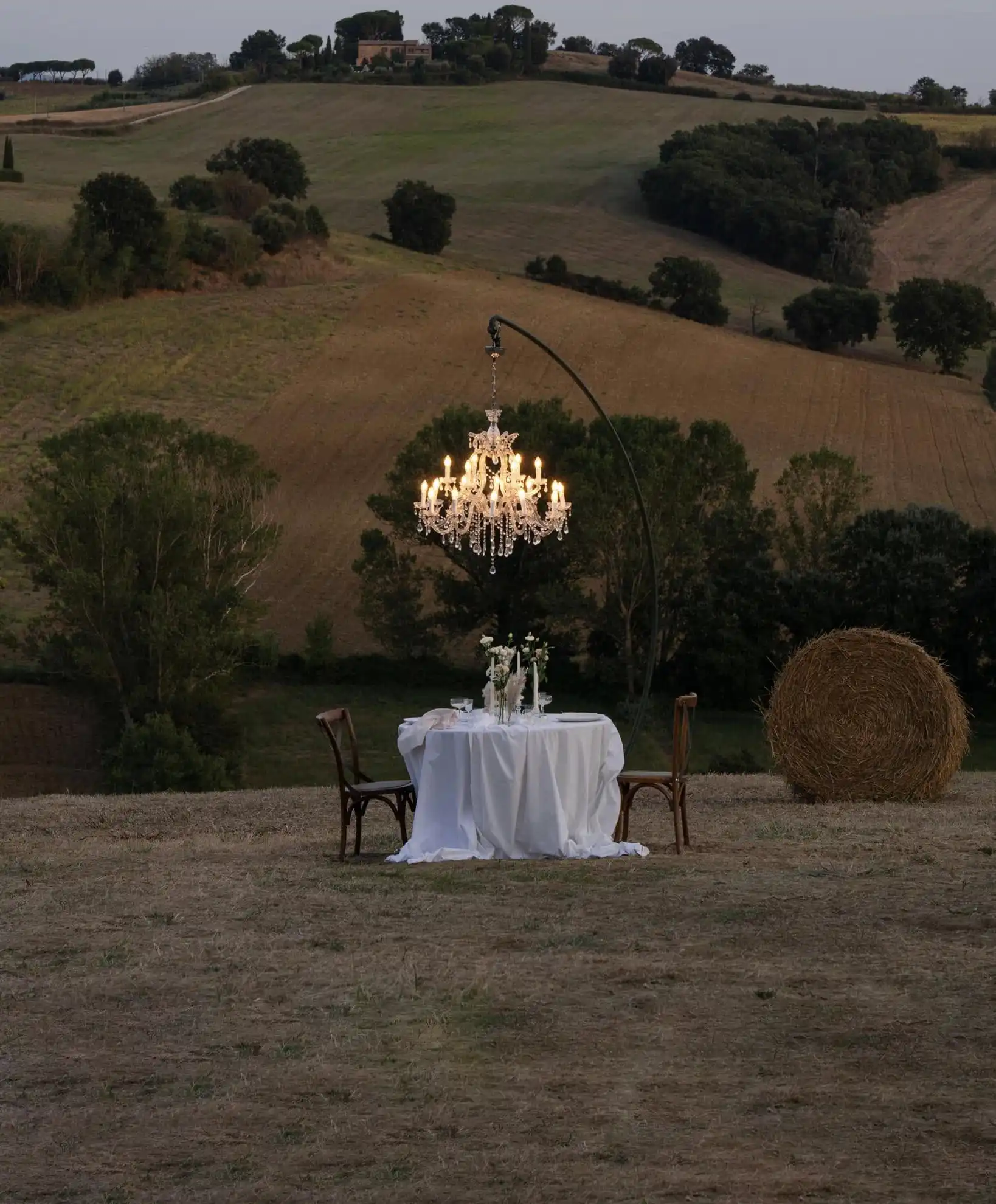 Elopement haut de gamme en Gironde organisé par L'envolée du moment : dîner privé avec lustre en cristal dans un champ face aux vallons, illustrant une expérience événementielle exclusive et créative.